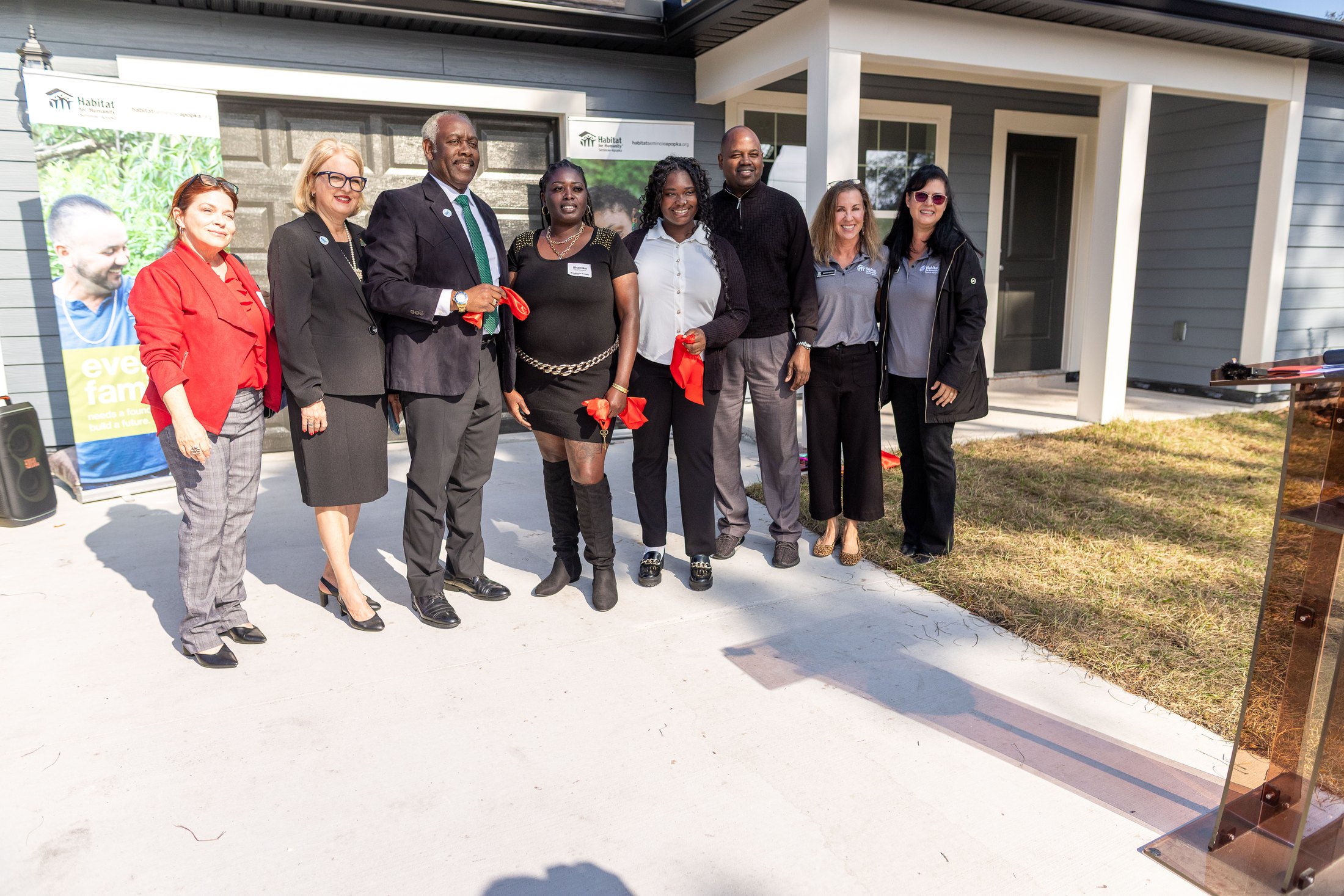 Participants posing outside the home with pieces of red ribbon.
